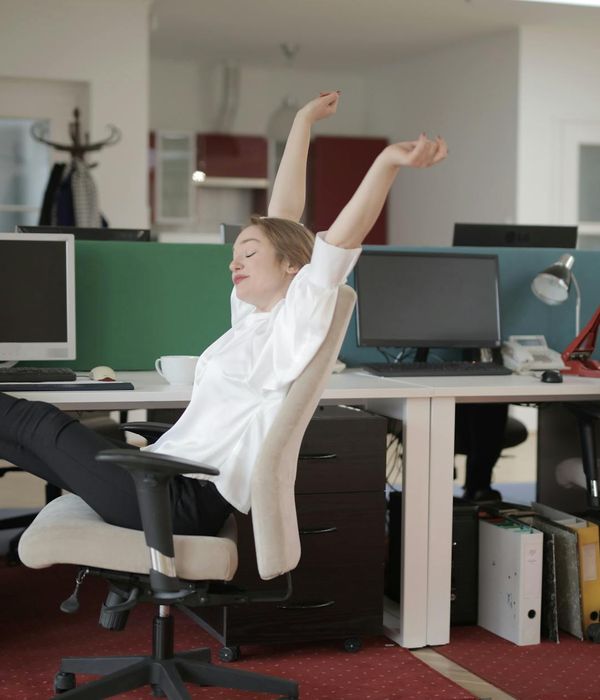 A woman in a calm stretching pose near her office desk.
